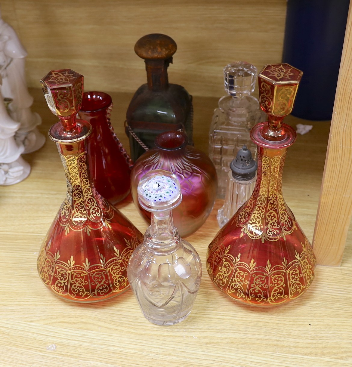 A pair of Bohemian gilded ruby glass decanters and stoppers, a Bohemian ‘millefiori paperweight’ stopper and associated decanter and mixed glass